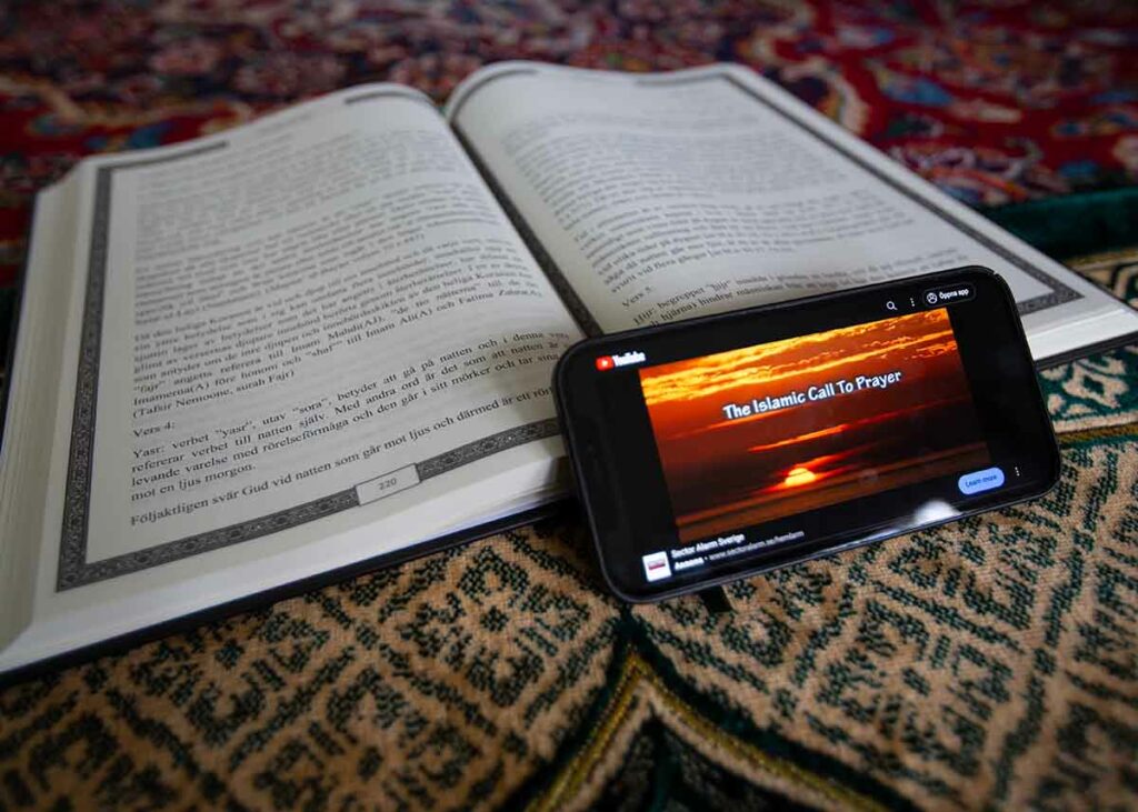 Böneutrop, adhan. Bild på Koran och iPhone som spelar upp ett böneutrop från YouTube.